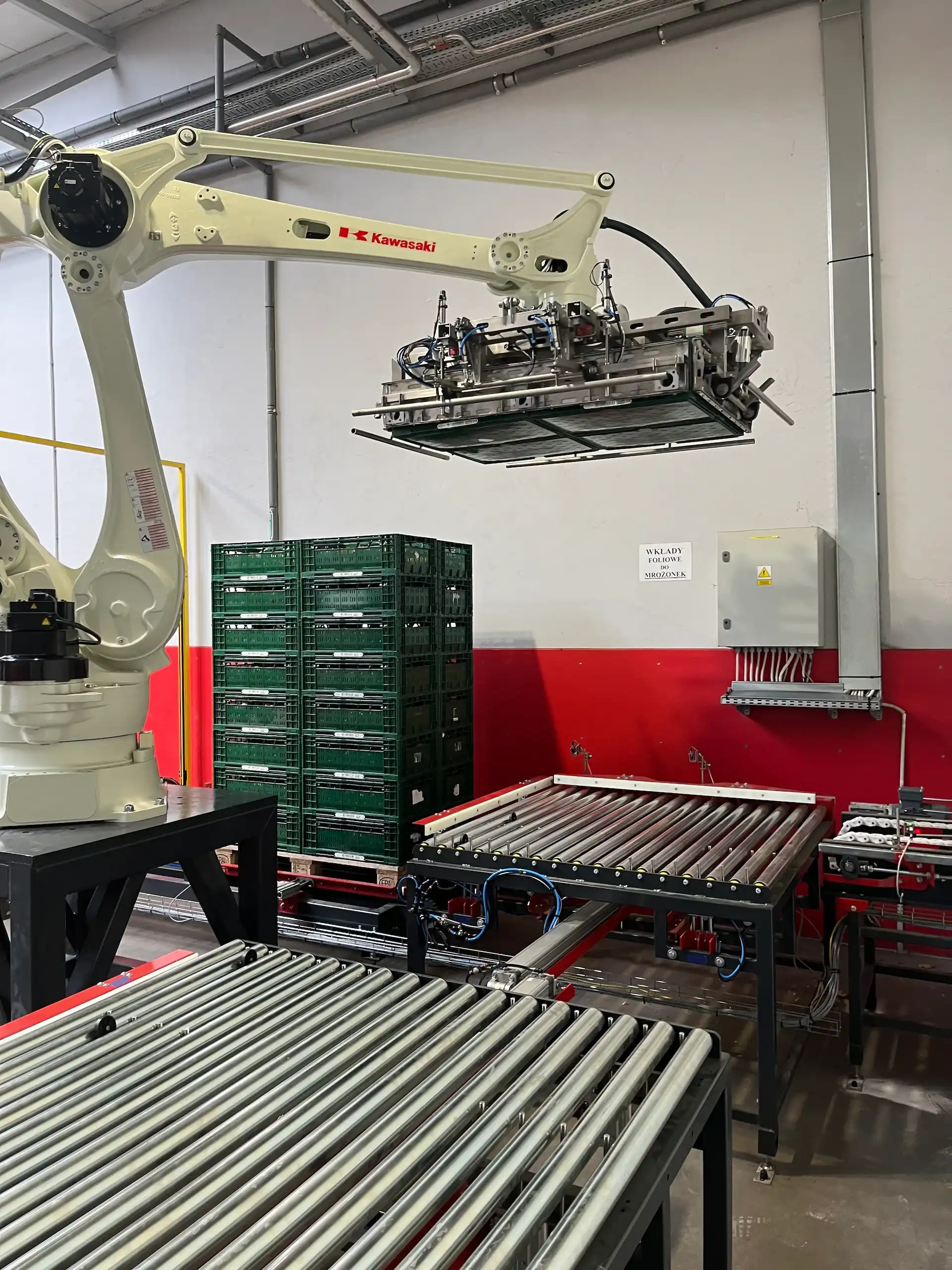 Zautomatyzowane stanowisko z robotem układającym skrzynki z cebulą na palecie.